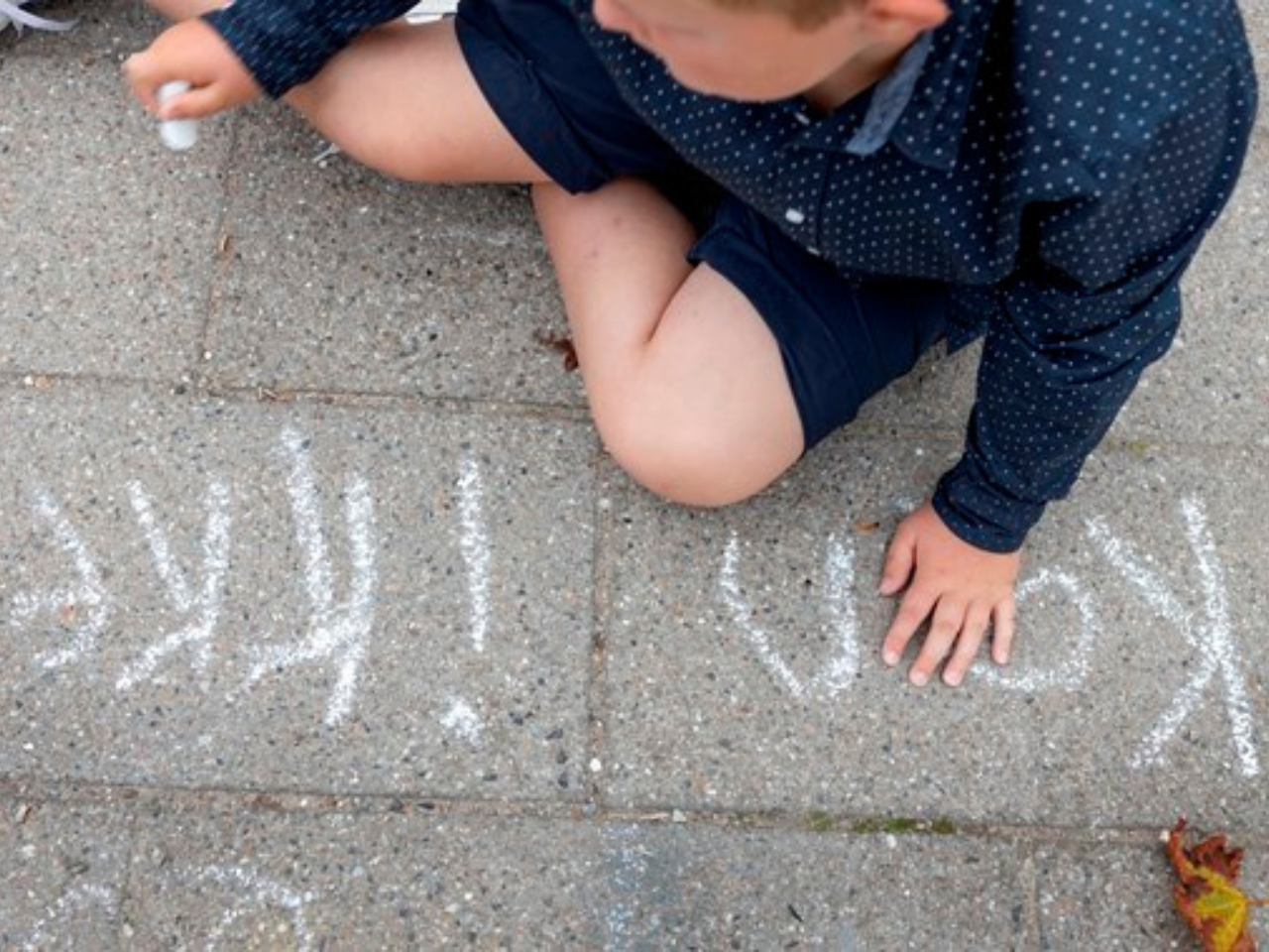 dreng skriver 'kan ikke' med kridt på asfalt