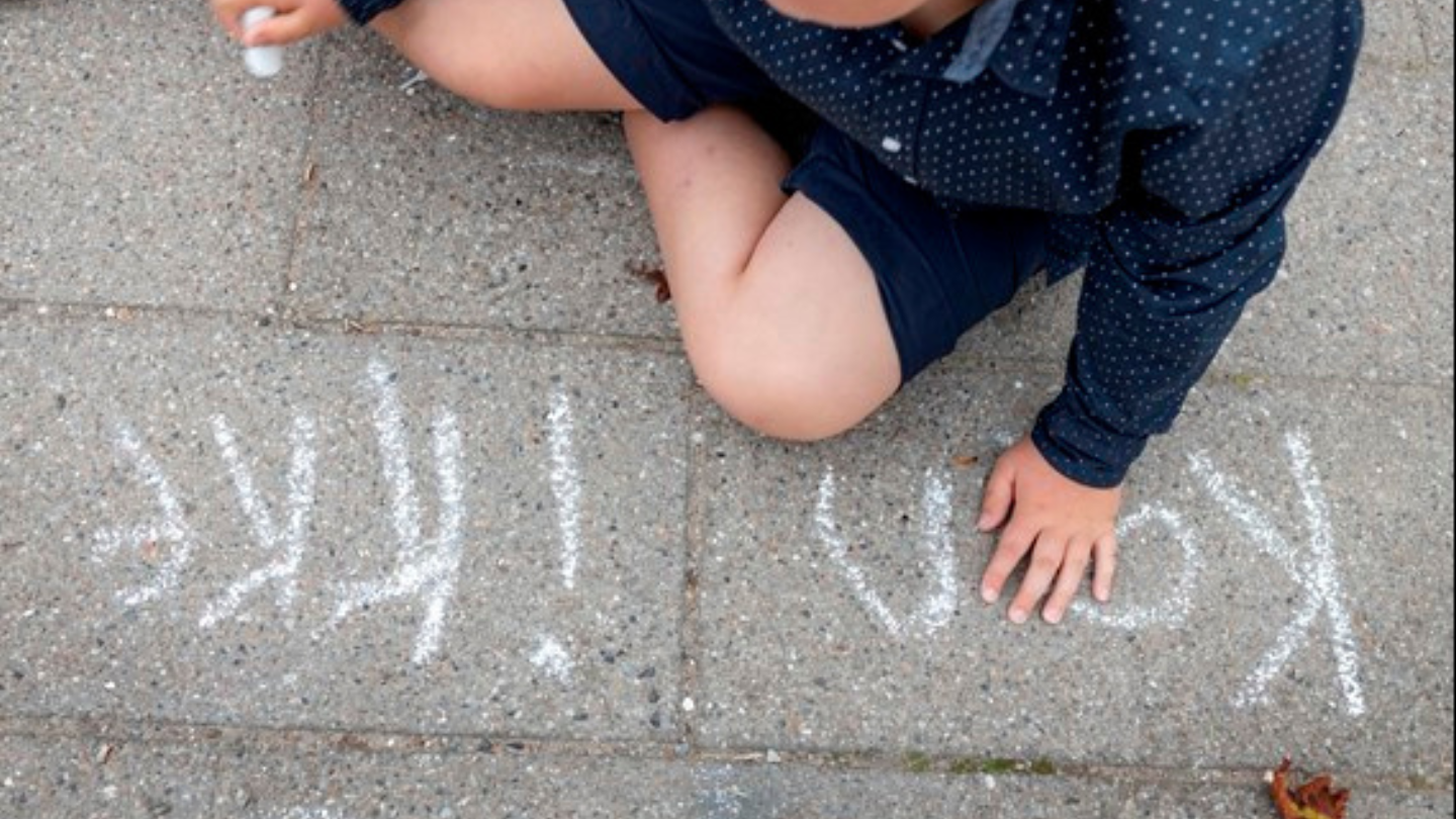 dreng skriver med kridt på asfalt