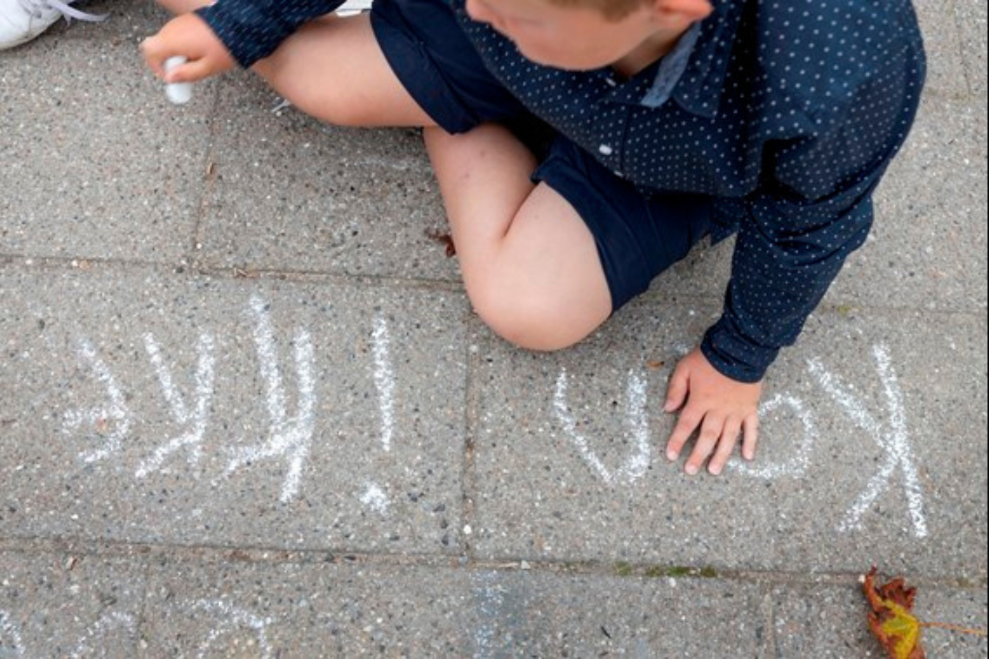 dreng skriver 'kan ikke' med kridt på asfalt