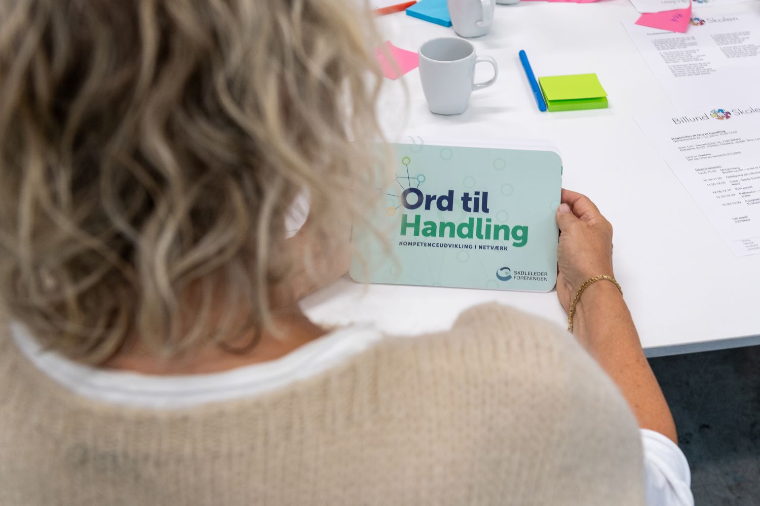 Et billede af en kvinde der sidder og læser på et kort med teksten Ord til handling